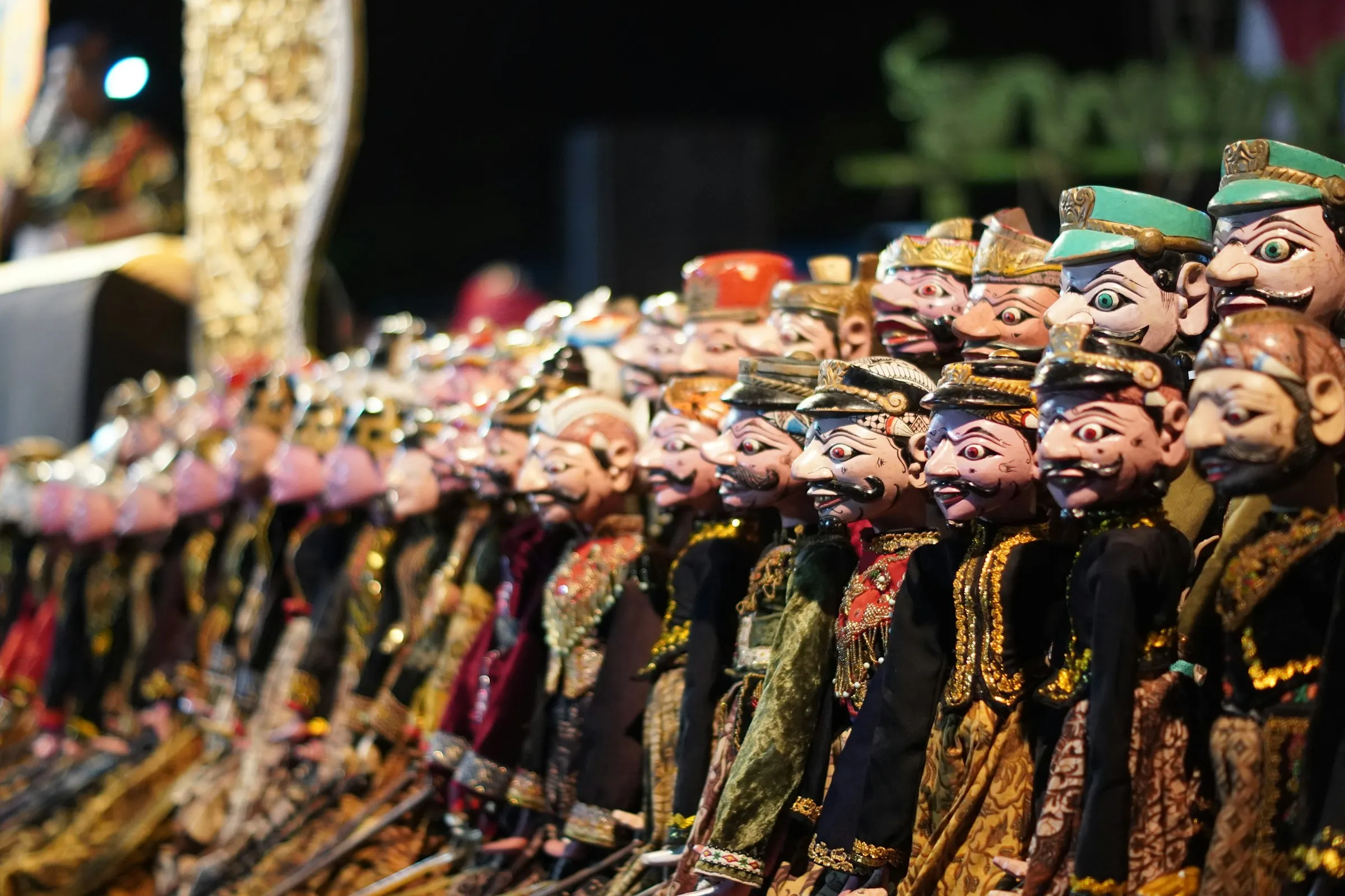 A row of traditional Sundanese wayang golek puppets on display, showing their distinctive carved faces and costumes